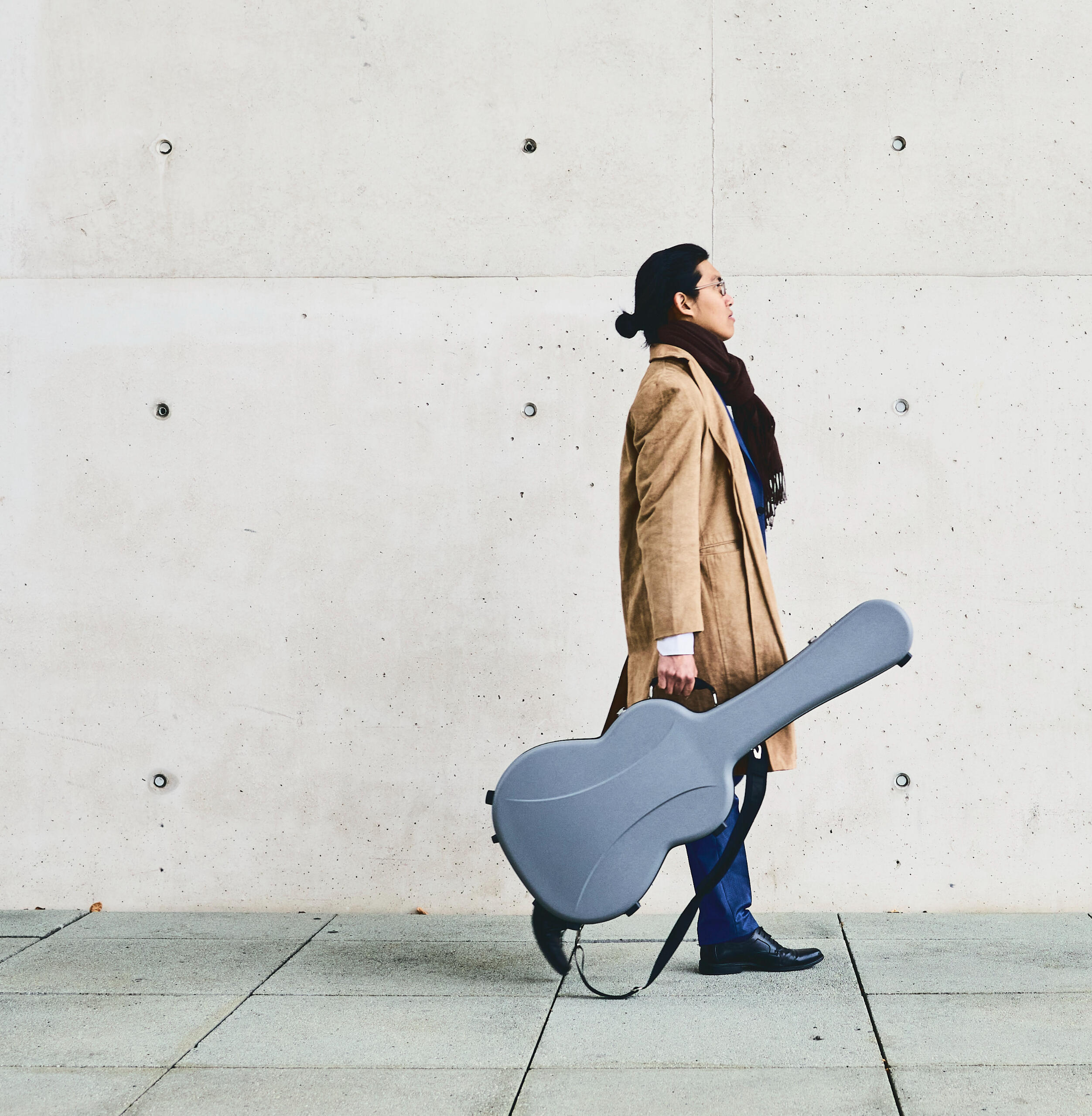 Person walking with a classical guitar case in the hand
